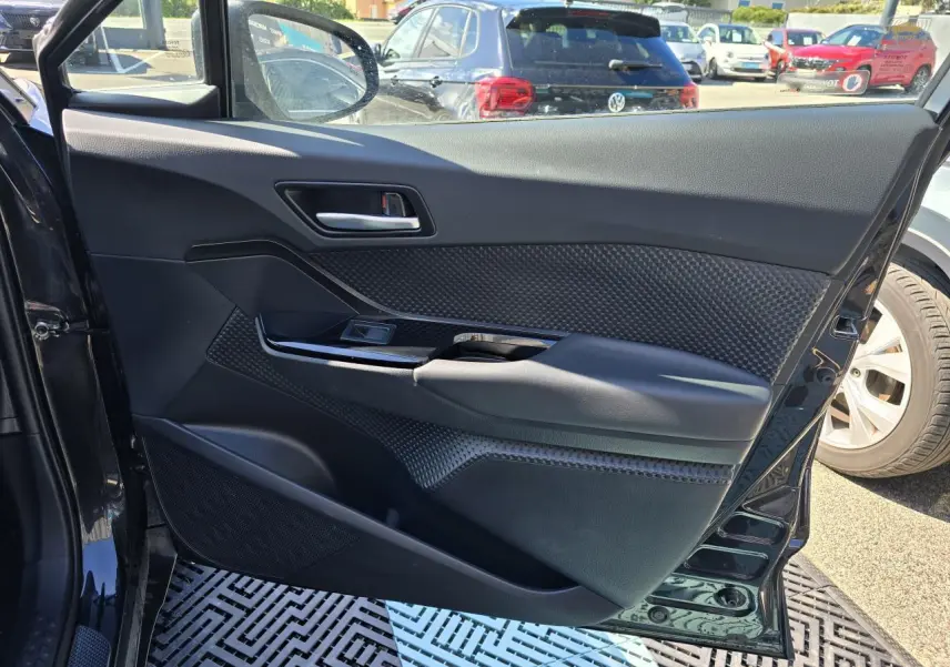 Porte avant gauche ouverte d'un Toyota C-HR noir métal, montrant le panneau intérieur avec poignée et commande de vitre.