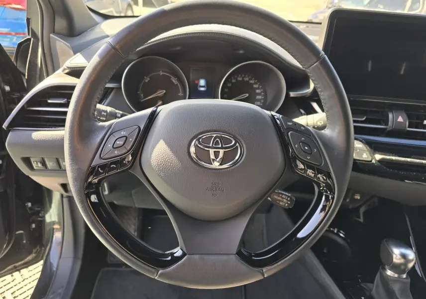Volant cuir noir multifonction de Toyota C-HR 1.8 Hybride 2023 vu de face avec tableau de bord et écran tactile.