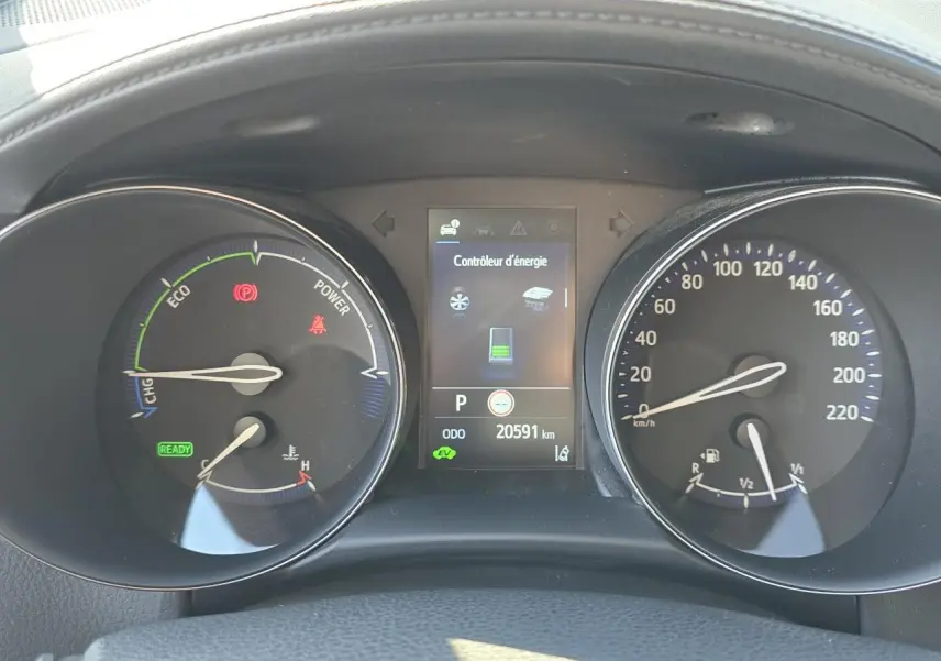 Tableau de bord du Toyota C-HR hybride 2023 avec écran central et compteurs analogiques en vue frontale.