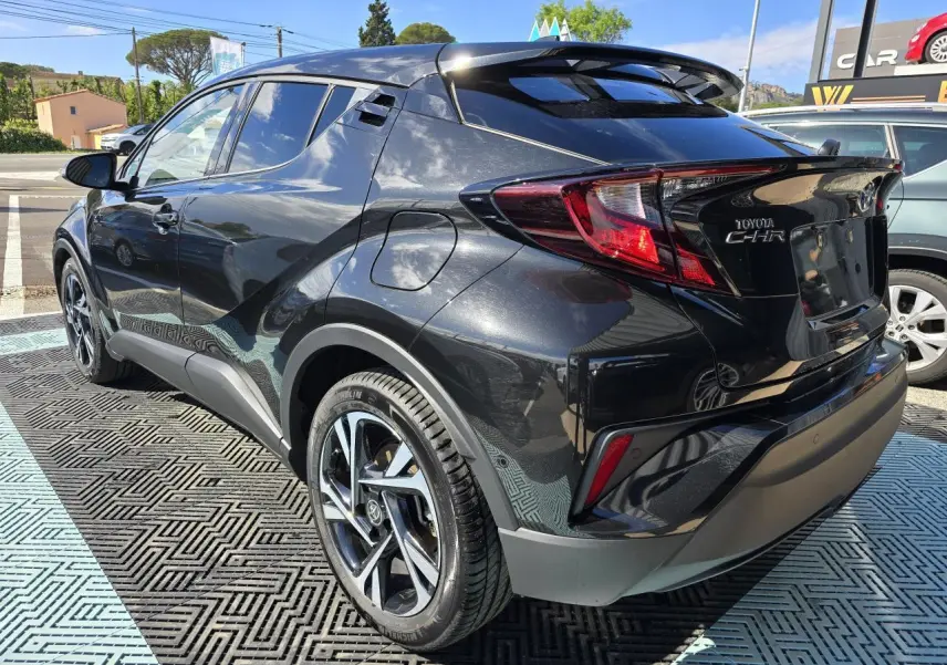 Toyota C-HR noir métal en 3/4 arrière droit, avec jantes alliage 18 pouces et becquet avant couleur carrosserie.