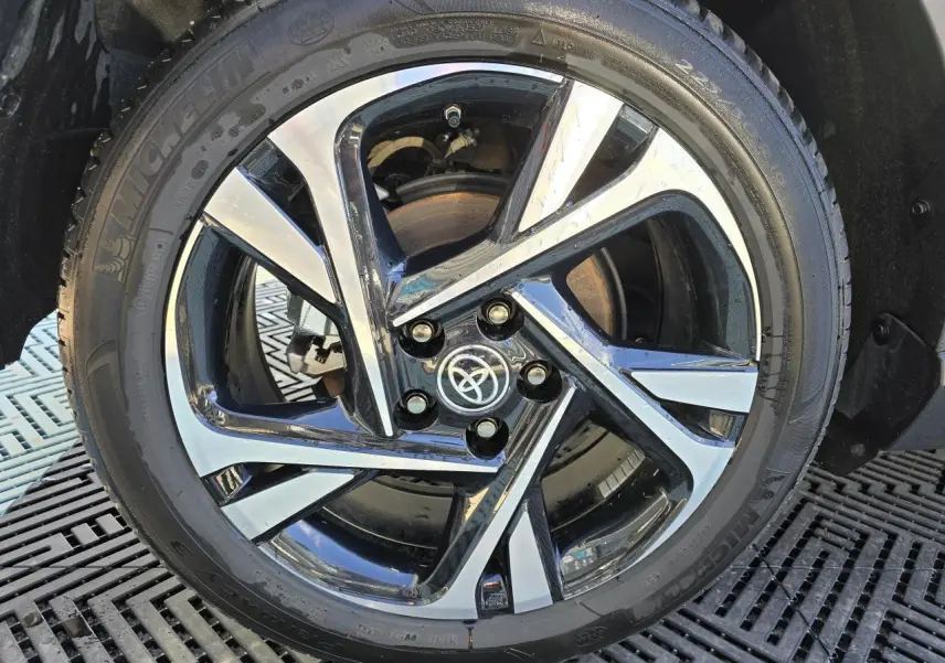 Gros plan sur la jante alliage 18 pouces bicolore du Toyota C-HR noir métal 2023 avec logo Toyota central.