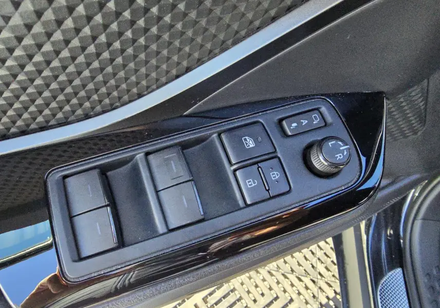 Panneau de commandes des vitres et rétroviseurs côté gauche sur porte noire métallisée d'un Toyota C-HR 2023.