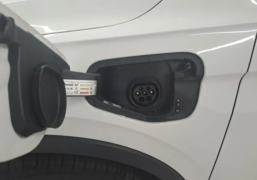 Prise de recharge ouverte côté avant gauche du Volkswagen Tiguan blanc pur 2023 hybride rechargeable R-Line.