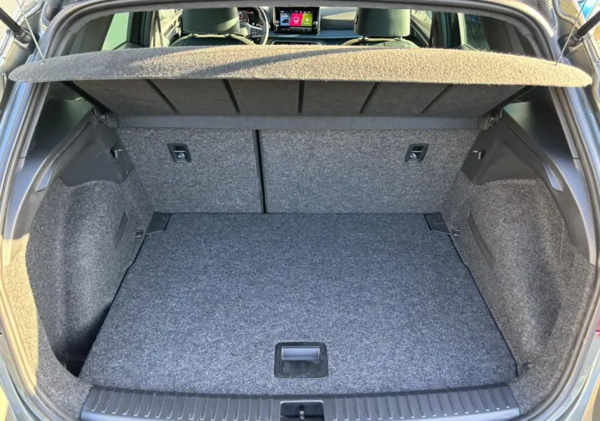Coffre ouvert vu de l'arrière d'un SEAT Arona gris Cliff, montrant le plancher à double fond et la plage arrière.