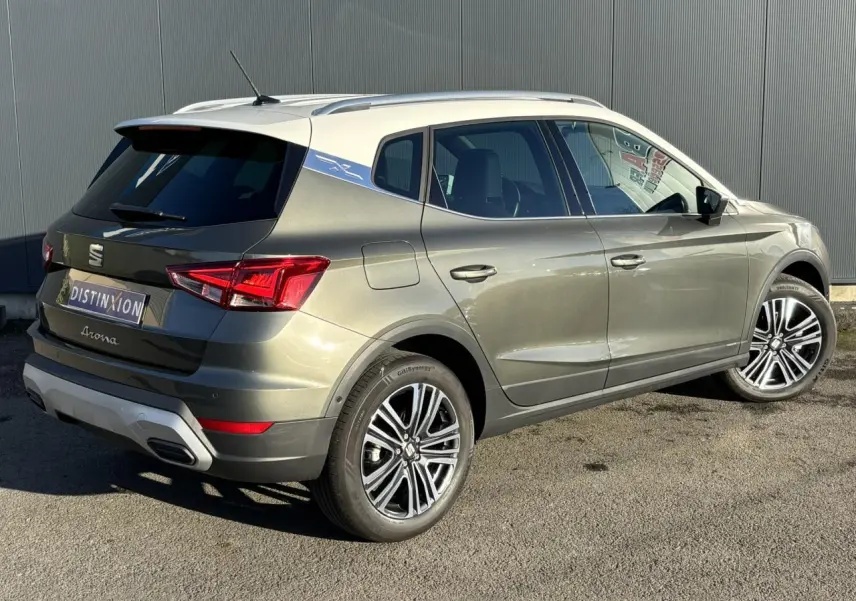 Vue 3/4 arrière droite d'un SEAT Arona gris Cliff avec toit blanc et jantes alliage 17 pouces, en extérieur.