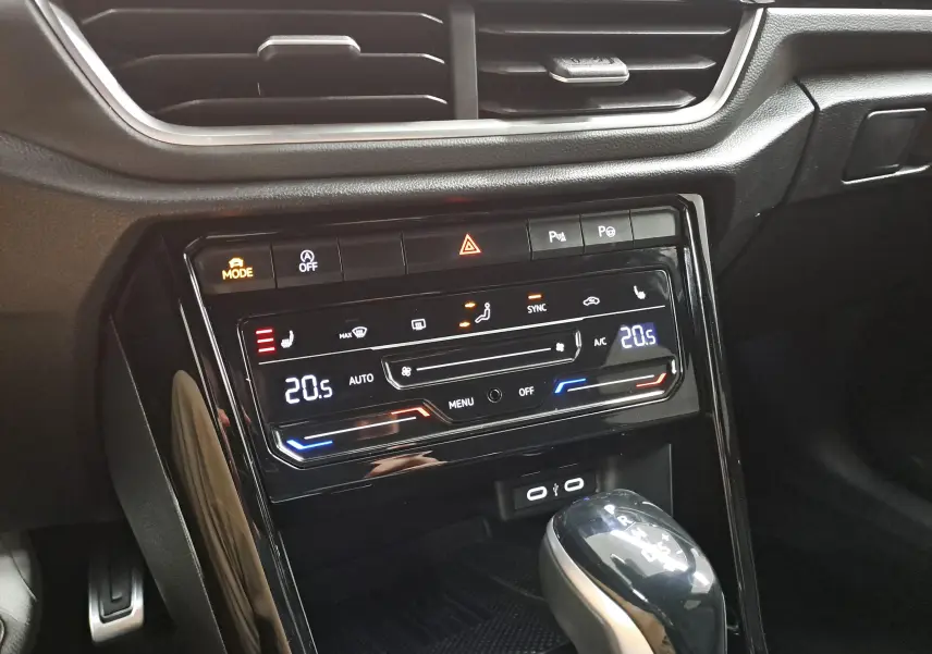 Gros plan sur la console centrale du Volkswagen T-Roc 2025, avec commandes climatisation digitales et levier de boîte auto.