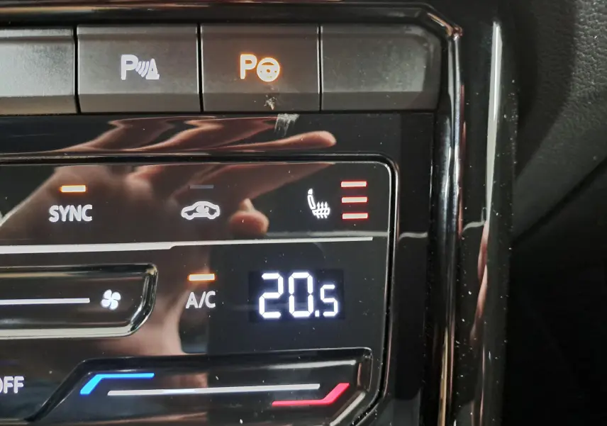 Gros plan sur la commande de climatisation avec affichage digital à 20,5°C et bouton siège chauffant actif.