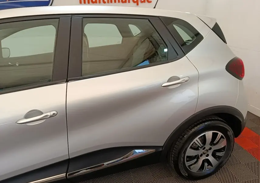 Vue latérale droite d'un Renault Captur gris clair, mettant en valeur la porte arrière et la roue arrière avec jante stylisée.