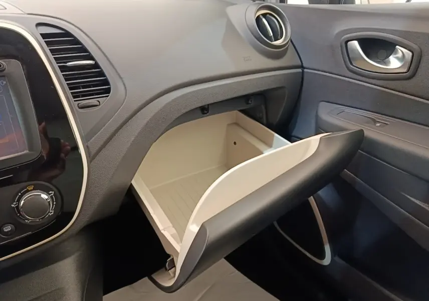 Vue intérieure côté passager du coffre à gants ouvert du Renault Captur Zen TCe 90 gris clair, avec tableau de bord noir.