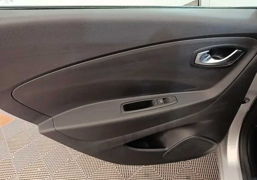 Vue intérieure côté gauche de la porte avant d’un Renault Captur gris clair avec commande de vitre et poignée intégrée.