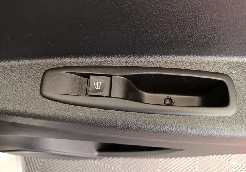 Gros plan sur le bouton de commande de lève-vitre noir intégré à la porte intérieure côté conducteur du Renault Captur gris clair.