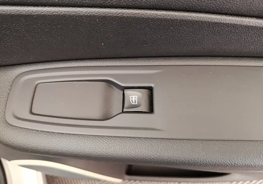 Gros plan sur le bouton de commande de la vitre électrique côté conducteur du Renault Captur gris clair 2018.
