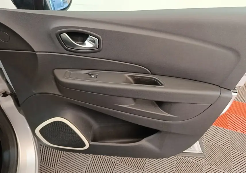 Vue rapprochée de la porte intérieure côté conducteur du Renault Captur gris clair avec haut-parleur intégré et poignée argentée.