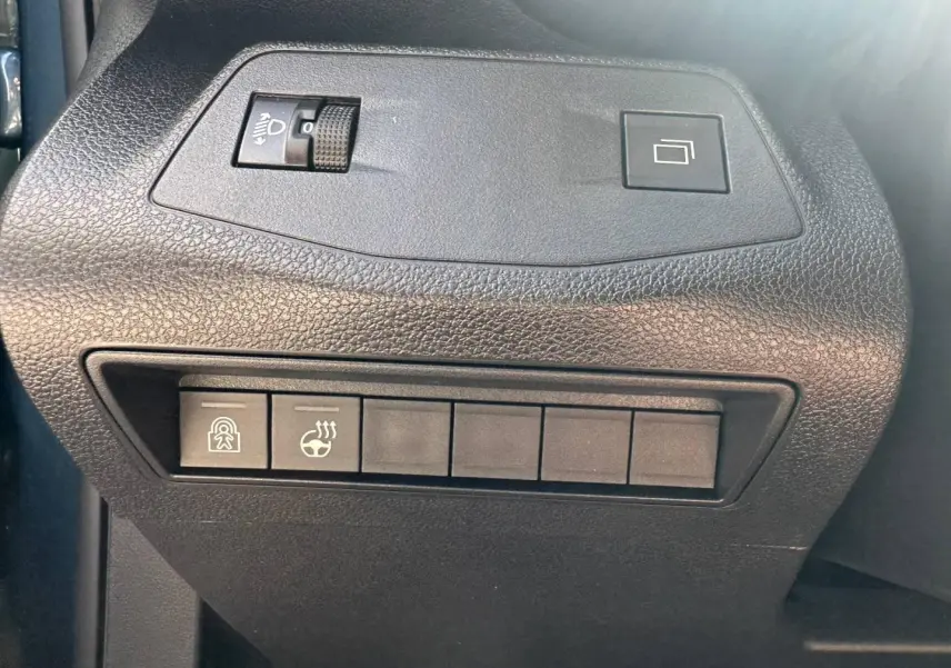 Gros plan sur les commandes de réglage des phares et du volant chauffant à gauche du tableau de bord du Citroën Berlingo bleu.