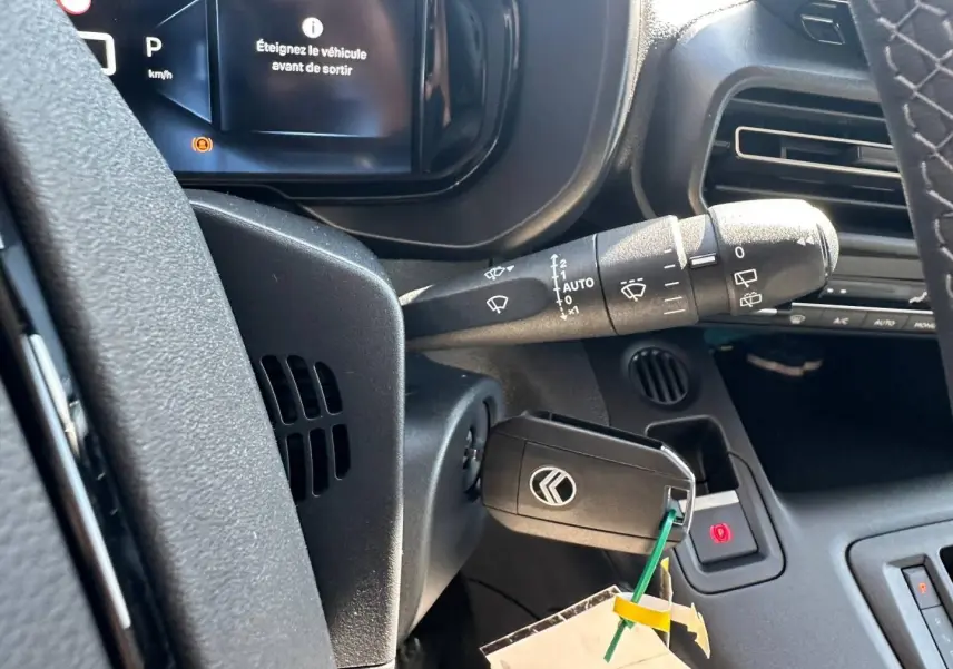 Gros plan sur le tableau de bord noir du Citroën Berlingo 2026 avec clé insérée et affichage digital indiquant d'éteindre le véhicule.