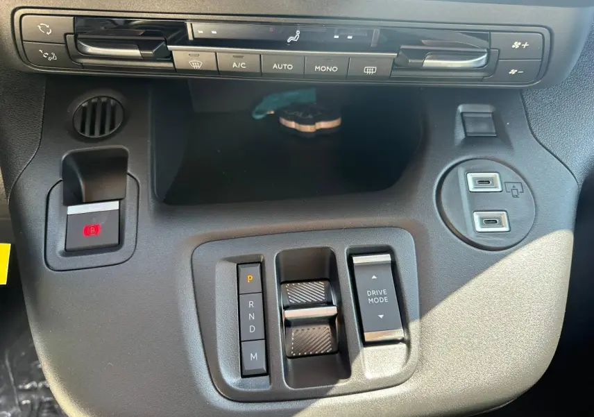 Vue rapprochée de la console centrale noire du Citroën Berlingo 2026 avec commandes de climatisation et boîte auto.