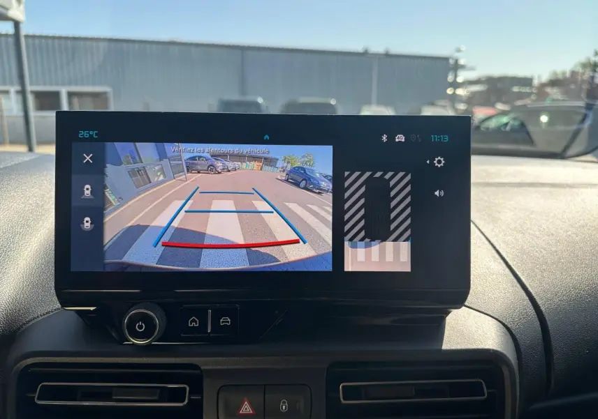 Écran tactile intérieur du Citroën Berlingo montrant la caméra de recul avec vue arrière sur parking et marquage au sol.