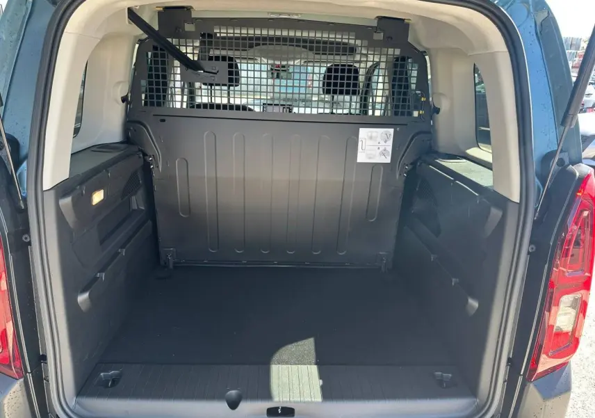 Coffre ouvert vu de l'arrière d'un Citroën Berlingo Kiama Blue avec séparation métallique et espace de chargement vide.