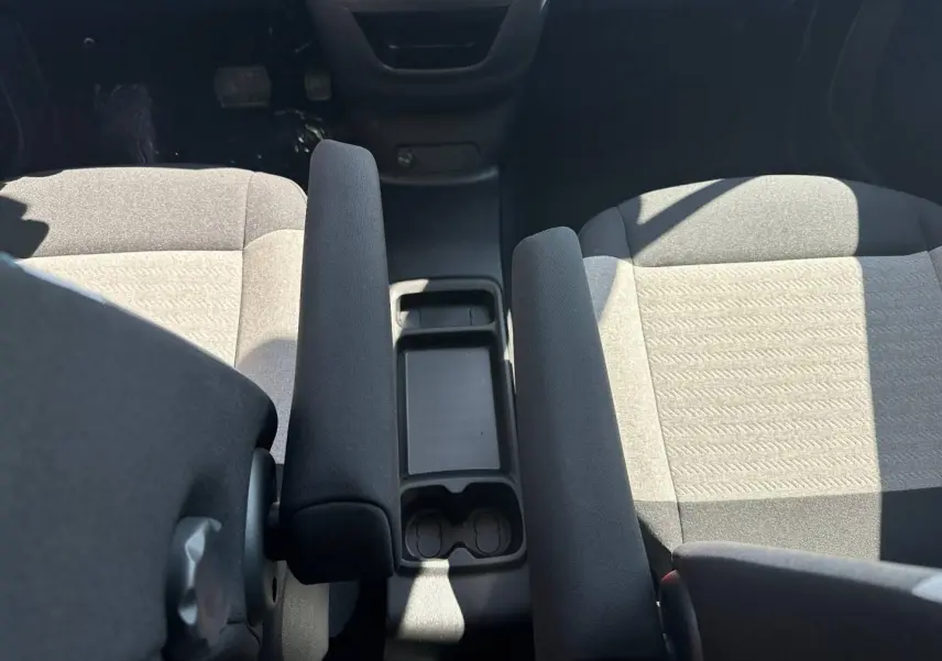 Vue intérieure rapprochée du Citroën Berlingo 2026, montrant les sièges avant gris et l'accoudoir central noir.