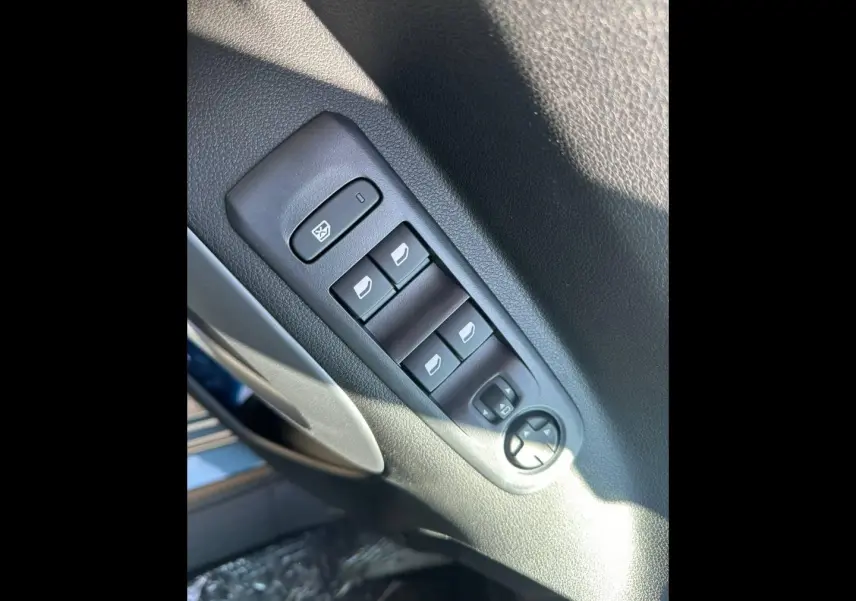 Gros plan sur les commandes des vitres électriques et rétroviseurs sur la porte côté conducteur d’un Citroën Berlingo bleu Kiama.