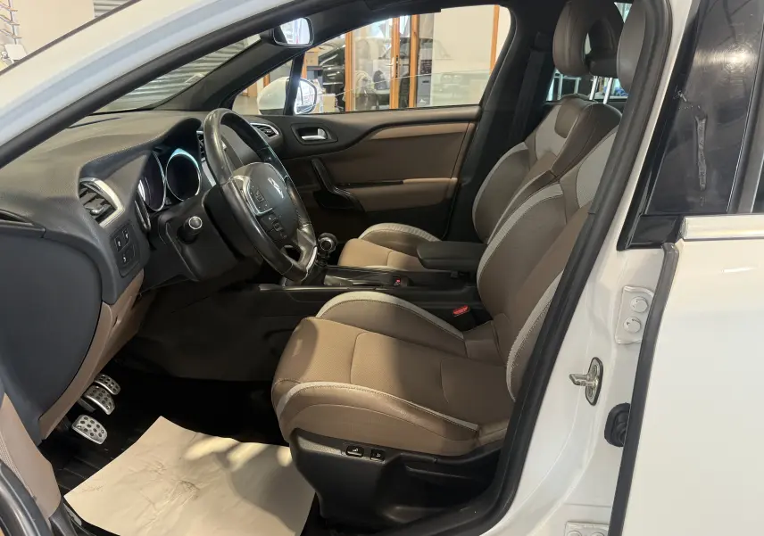 Intérieur côté conducteur d'une Citroën DS4 blanche 2012, montrant sièges beige et volant avec boîte manuelle.