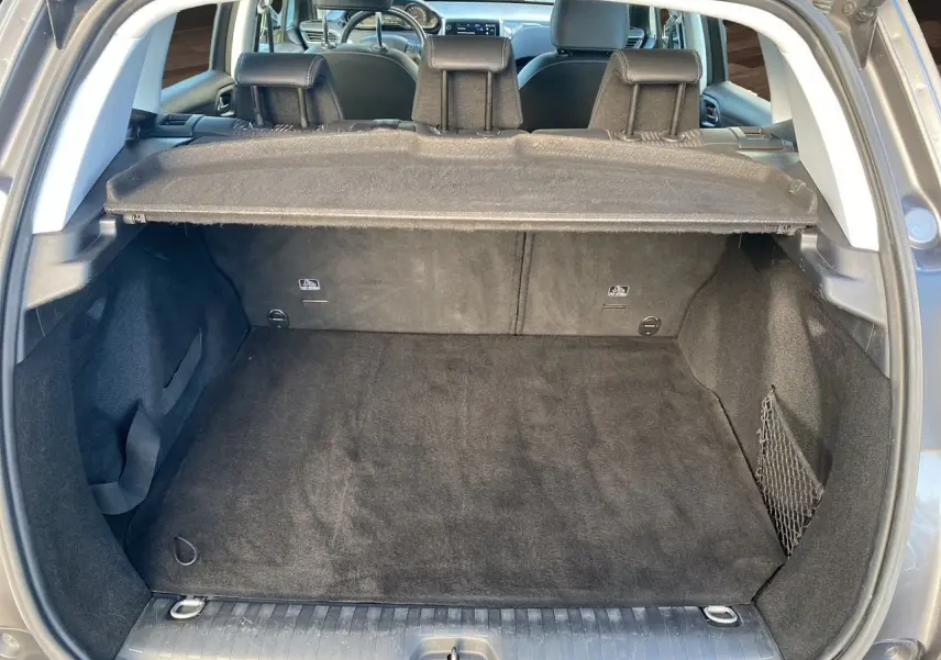 Coffre ouvert en vue arrière d’un Peugeot 2008 gris platinium, montrant l’espace de chargement et la plage arrière.