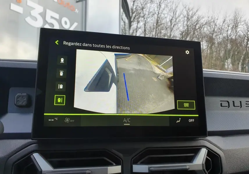Écran central du Dacia Duster blanc glacier montrant la caméra multivues avec vue latérale droite en stationnement.