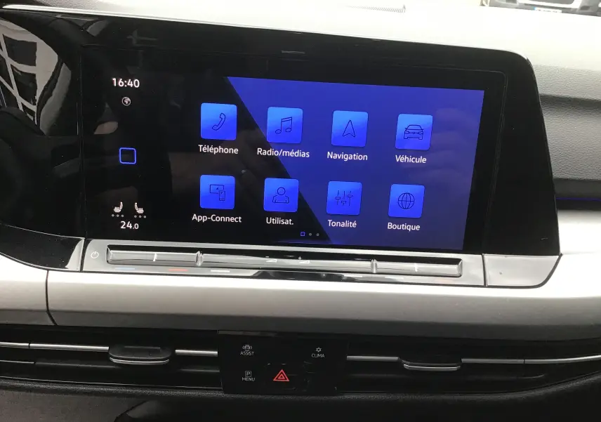 Écran tactile central bleu affichant les options multimédias et navigation dans l’habitacle d’une Volkswagen Golf gris reflex.