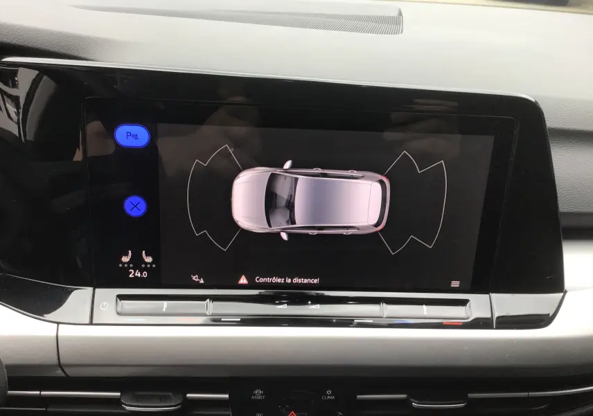Écran central de la Volkswagen Golf VIII gris reflex montrant l'aide au stationnement vue de dessus avec alertes de distance.