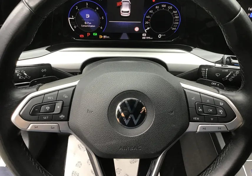 Vue rapprochée du volant noir et du tableau de bord numérique de la Volkswagen Golf VIII gris reflex, affichant le digital cockpit pro.