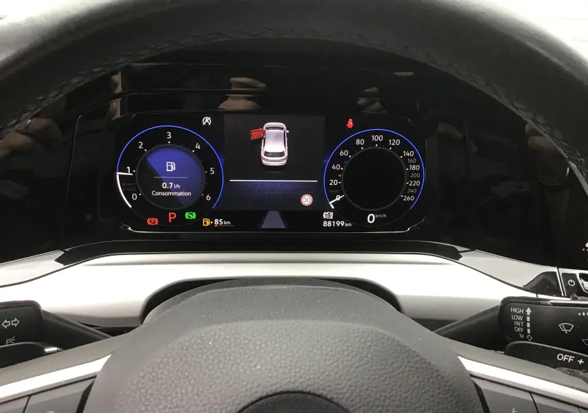 Vue rapprochée du tableau de bord digital pro de la Volkswagen Golf VIII avec affichage consommation et vitesse, volant en cuir noir.
