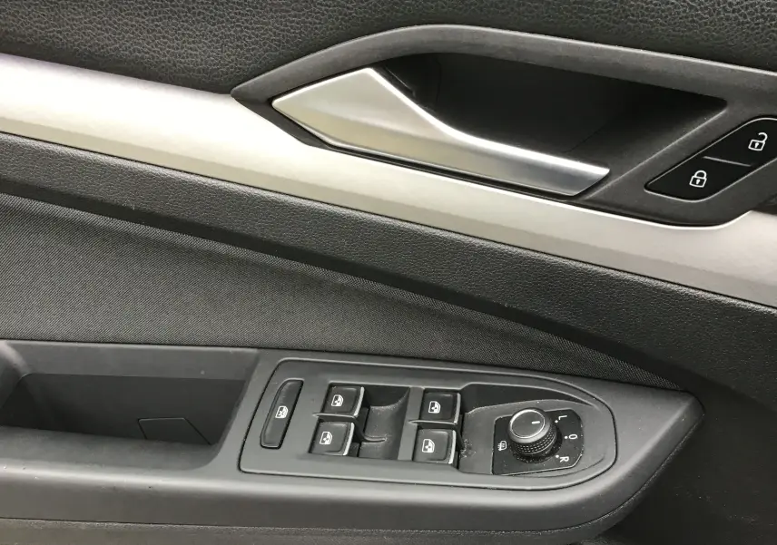 Gros plan sur la commande des vitres et rétroviseurs côté gauche de la porte intérieure d’une Volkswagen Golf VIII gris reflex.