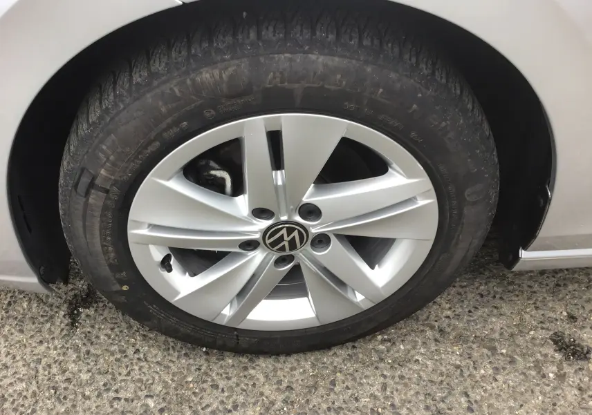 Gros plan sur la roue avant gauche d'une Volkswagen Golf VIII gris reflex avec jante alliage 16 pouces.