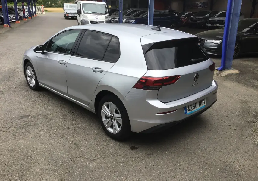 Volkswagen Golf VIII gris reflex vue 3/4 arrière droit, vitres teintées et jantes alliage 16 pouces visibles.
