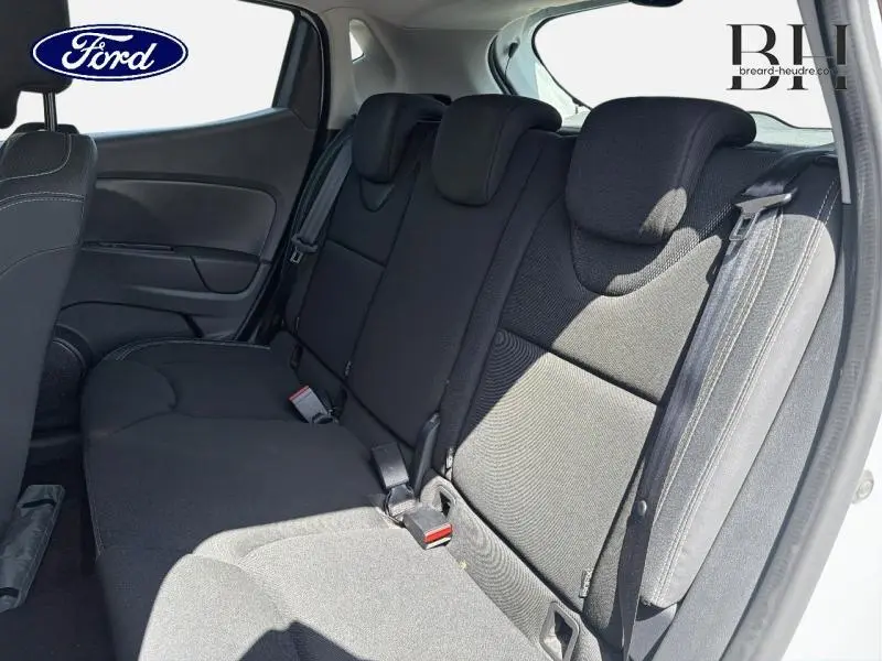 Vue intérieure de la banquette arrière noire d'une Renault Clio blanche, avec ceintures de sécurité visibles.