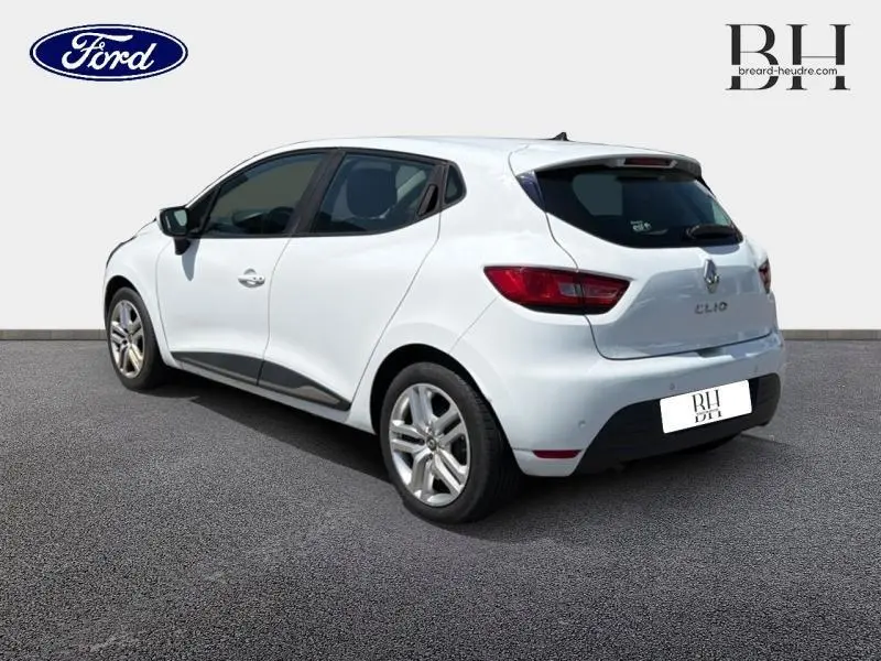 Vue 3/4 arrière droite d'une Renault Clio blanche 2018 avec becquet arrière et vitres teintées.
