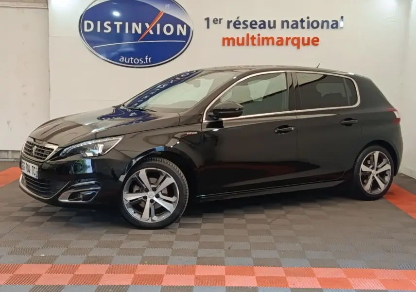 Vue latérale droite d'une Peugeot 308 noire GT Line 2016, avec jantes alliage et phares LED visibles en intérieur showroom.