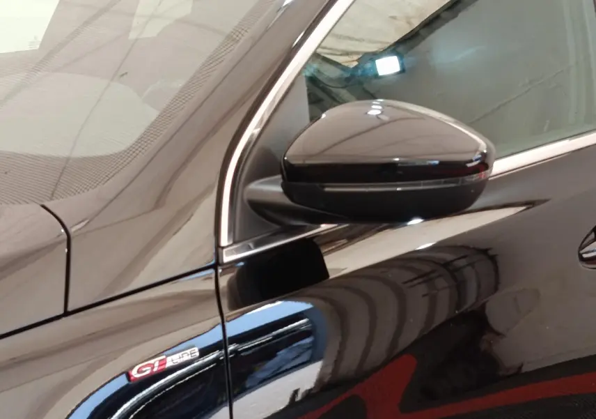 Gros plan sur le rétroviseur droit et l’emblème GT Line d’une Peugeot 308 noire, vue côté droit.