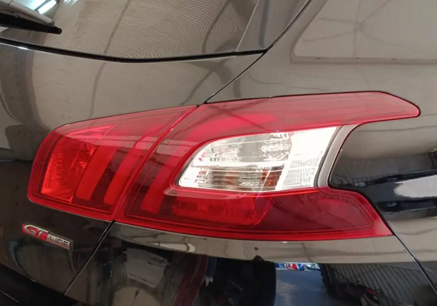 Gros plan sur le feu arrière droit rouge et blanc d’une Peugeot 308 GT Line noire de 2016.
