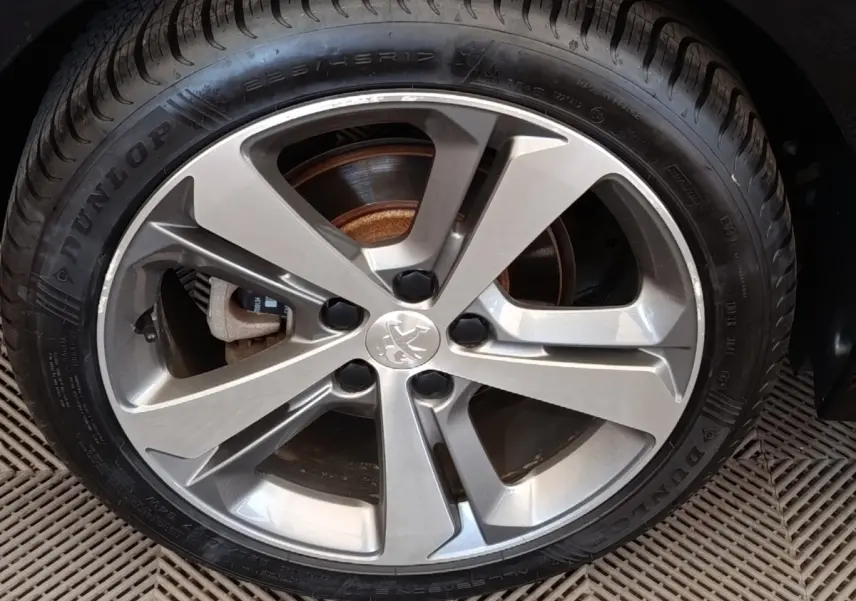 Gros plan sur la jante alliage argentée et pneu Dunlop d'une Peugeot 308 noire de 2016.
