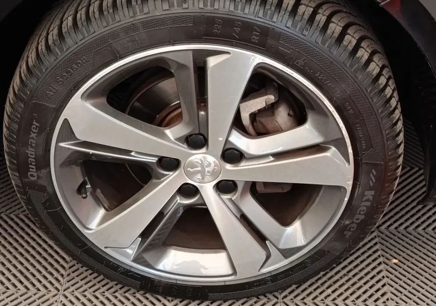 Gros plan sur la jante alliage argentée avec logo Peugeot au centre, montée sur pneu Kleber All Season.