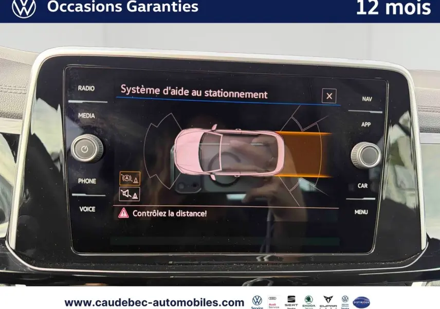 Vue rapprochée de l’écran tactile du Volkswagen T-Roc Cabriolet noir affichant l’aide au stationnement active.