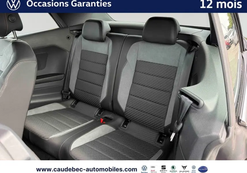 Vue intérieure arrière des sièges du Volkswagen T-Roc Cabriolet 2025, tissu noir et gris avec ceintures visibles.