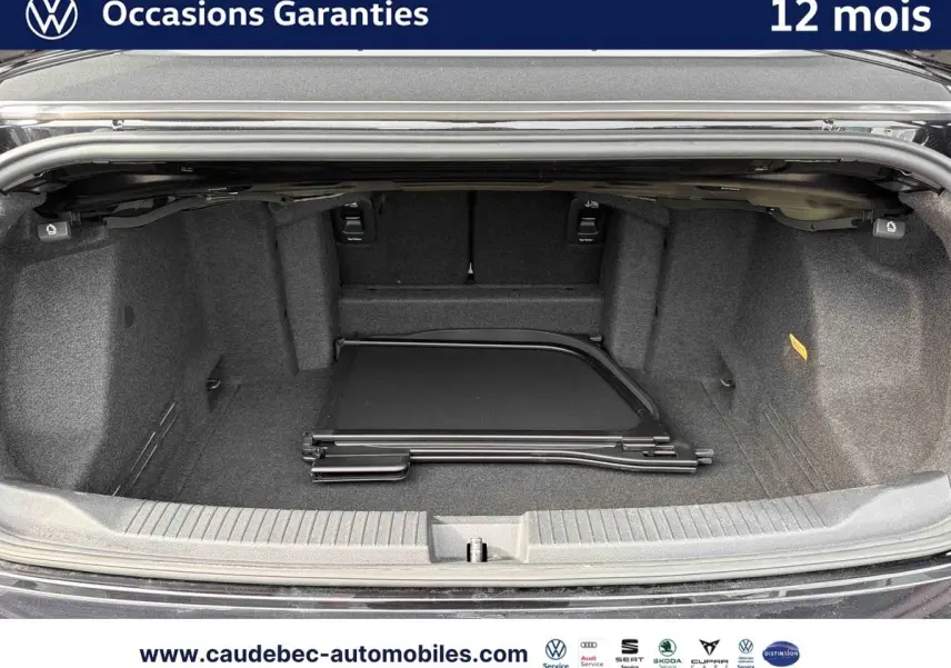 Coffre ouvert du Volkswagen T-Roc Cabriolet noir, vue intérieure montrant un filet de séparation plié au sol.