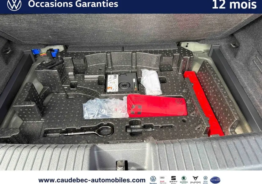 Coffre ouvert du Volkswagen T-Roc Cabriolet noir, montrant le rangement avec kit de secours et outils intégrés.