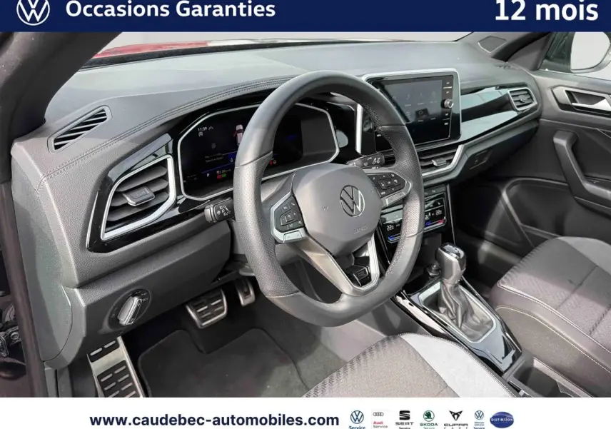 Intérieur avant droit du Volkswagen T-Roc Cabriolet noir, volant cuir multifonction et écran tactile central visible.
