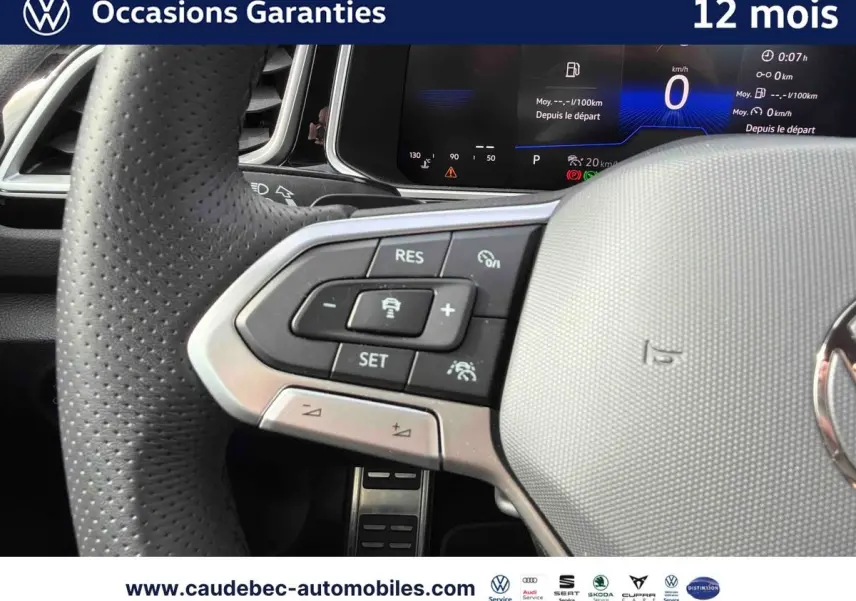 Gros plan sur le volant cuir perforé du Volkswagen T-Roc Cabriolet noir avec commandes multifonctions et tableau de bord digital.