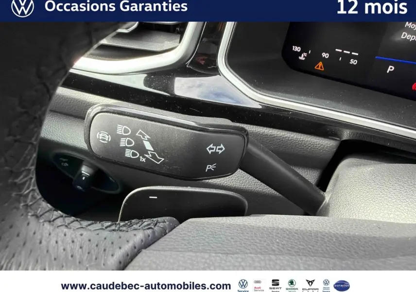 Gros plan sur le commodo gauche du volant en cuir perforé du Volkswagen T-Roc Cabriolet noir, avec tableau de bord numérique visible.