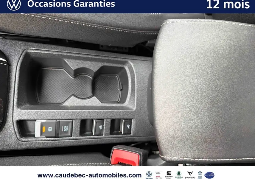 Vue plongeante sur la console centrale noire du Volkswagen T-Roc Cabriolet 2025 avec accoudoir et commandes électriques.
