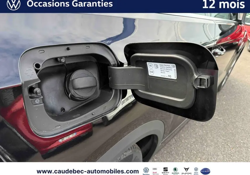 Vue rapprochée du bouchon de réservoir essence ouvert côté gauche sur Volkswagen T-Roc Cabriolet noire 2025.